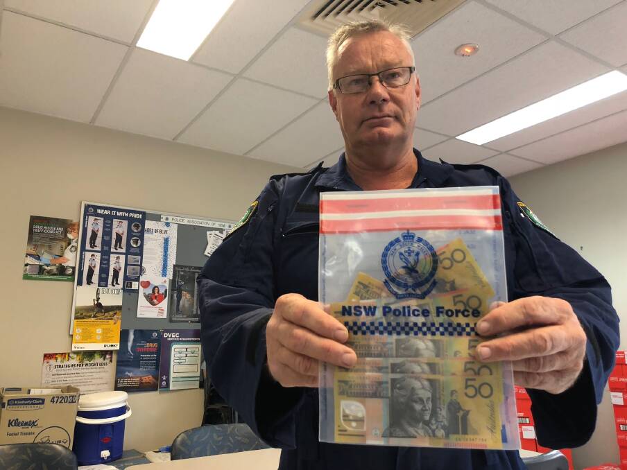 PICTURED: Senior Constable Alan Cope holding counterfeit cash discovered at a Griffith Hotel last month. PHOTO: Jacinta Dickins
