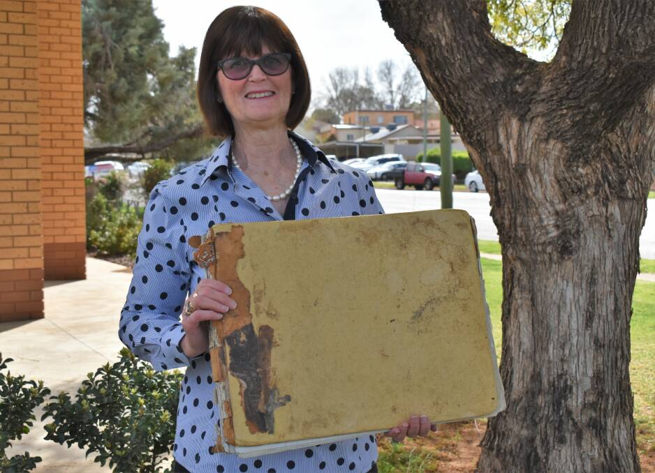 PIECE OF HISTORY: Carol Collier holding the Collier Trenerry burial register which dates back to 1929. PHOTO: Shaun Paterson