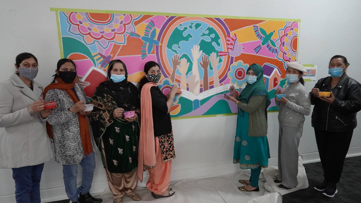 TOGETHER: Gurpreet Kaur, Saiqa, Taj Begum, Dalveer Kaur, Sonifa Khatun Salma, Huong Tran and Kitty Tengere in front of the mural. PHOTO: Monty Jacka