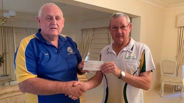 GIVING: Darlington Point Lions Club member Allan Strachan hands over the $10,000 to Griffith Can Assist's Ron Anson. Photo: Supplied.