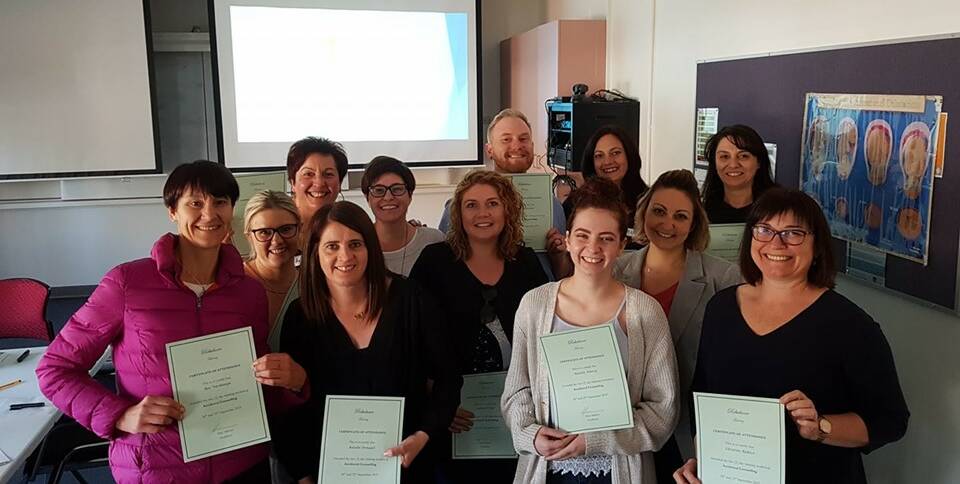 ACCIDENTAL COUNSELLORS: A group of hairdressers and massage therapists hold their certification aloft after completing the accidental counsellor course run in Griffith earlier in the month. PHOTO: Supplied