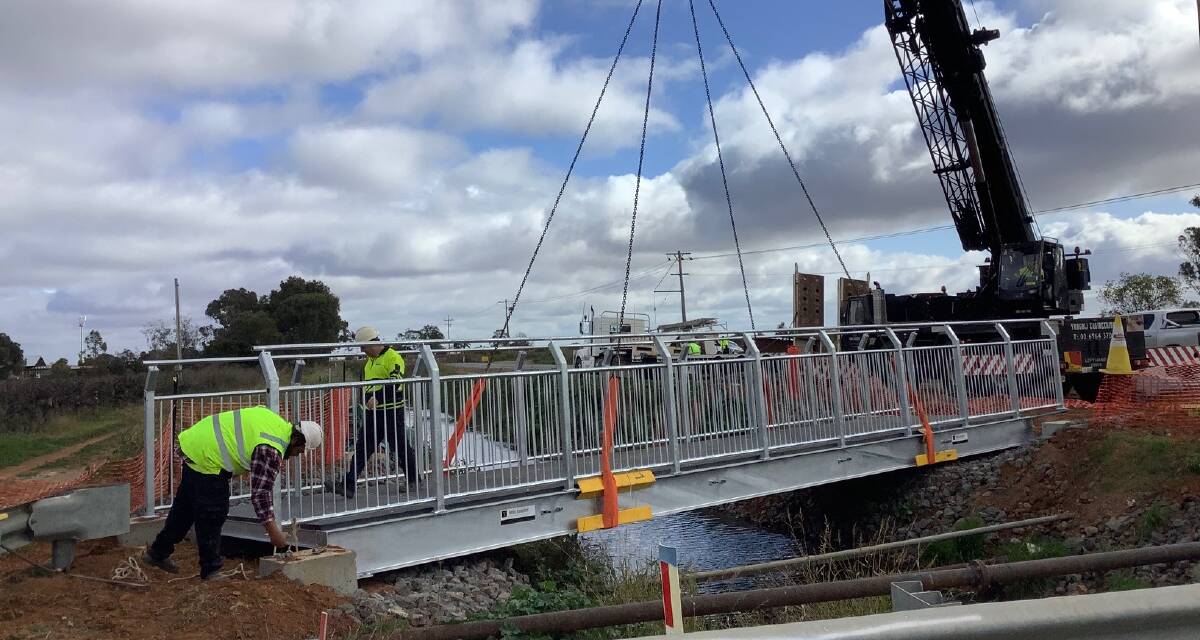 BUILDING BRIDGES: A bridge is lowered over the drainage channel at the intersection of Beaumont Road and Kidman Way. PHOTO: Contributed