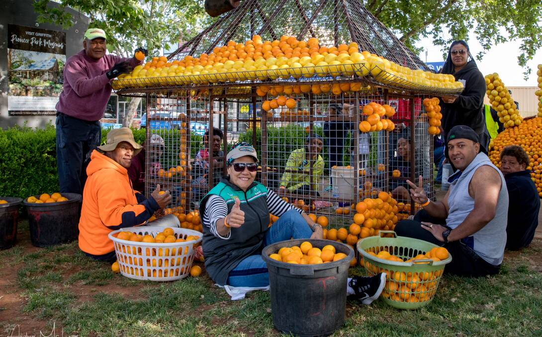 COMING DOWN: A group of volunteers help to construct the citrus sculptures along Banna Avenue, which will be coming down on Sunday. PHOTO: Supplied