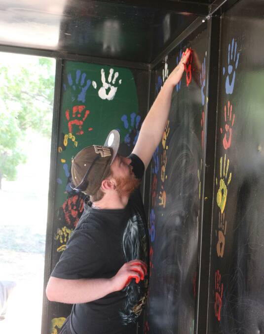 HELPING HAND: Harley O'Flaherty helps put a hand on the repainted bus shelter. PHOTO: Calhan Behrendt