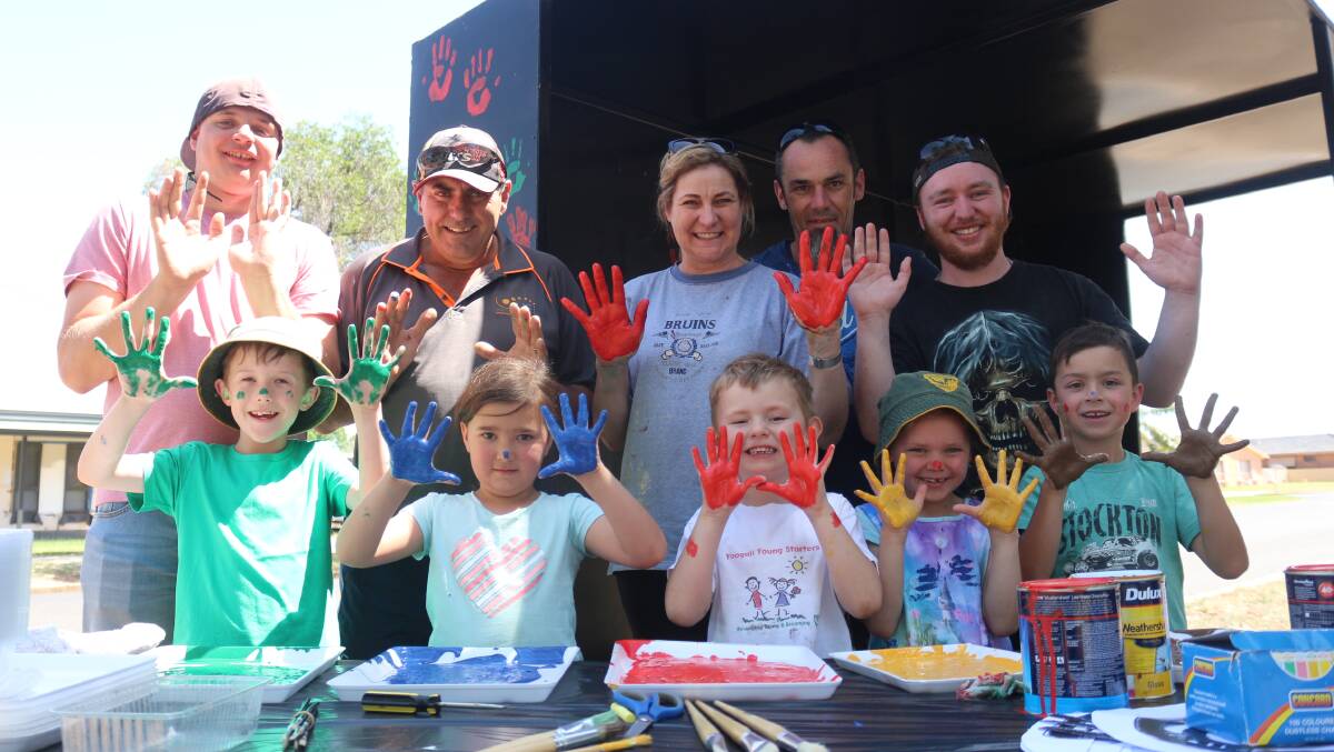 PAINT IT: Clients from Ningana Enterprises join in with Yoogali Public School students and principal Leanne McWhirter (back, centre) to help repaint the bus shelter which sits outside the school. PHOTO: Calhan Behrendt