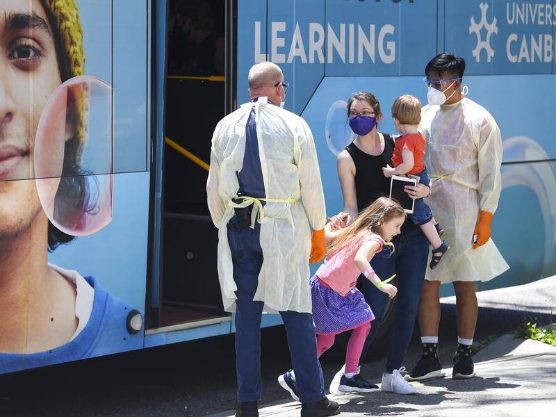 An Australian family exit a bus as they arrive for mandatory 14-day hotel quarantine in Canberra.