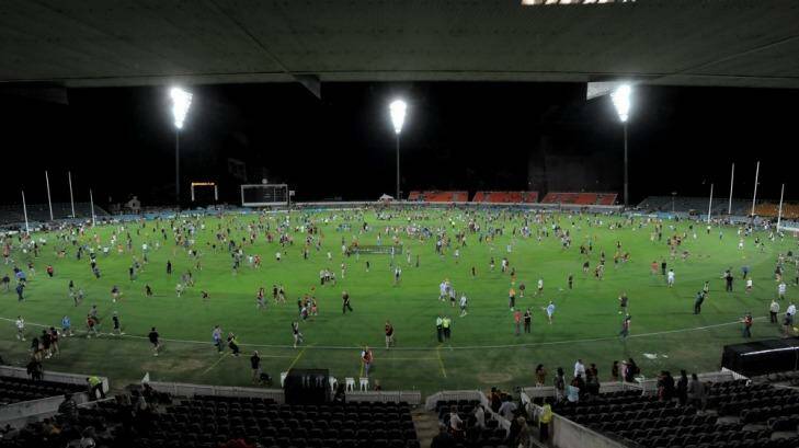 Fans get to kick the ball on the ground after a NAB Challenge game at Manuka Oval.  Photo: Graham Tidy