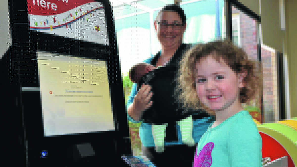 SELF SERVE: Rosemarie Borg, 3, checks out her own book at Griffith City Library with the help of the new RFID (Radio Frequency Identification) technology. Her mum Wendy and baby brother Caleb, 11 days, look on. 