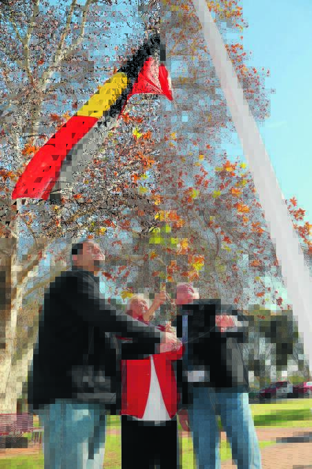 LEST WE 
FORGET: Callum Penrith, Aunty Heather Edwards and Mayor John Dal Broi raise the Aboriginal flag during NAIDOC Week celebrations in Griffith on Monday. Picture: Anthony Stipo