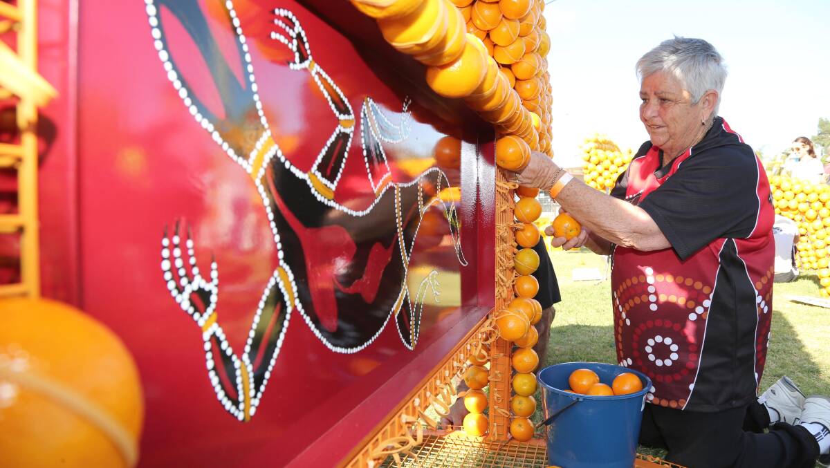 Volunteers help arrange hundreds and thousands of oranges for the Citrus Sculptures in 2014.