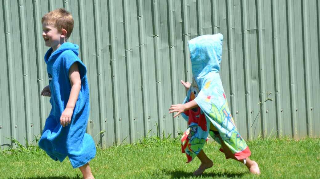 Archie Keough, 5, gets chased by Tom Shumack, 4, on Australia Day in Junee. Picture: Declan Rurenga