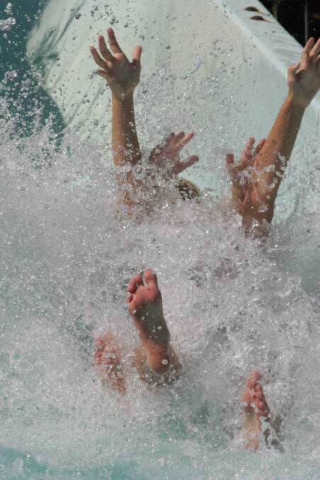 Lailani Watts and Charlotte Rudd, both nine, splash down at the bottom of the Leeton pool slide. Picture: John Gray