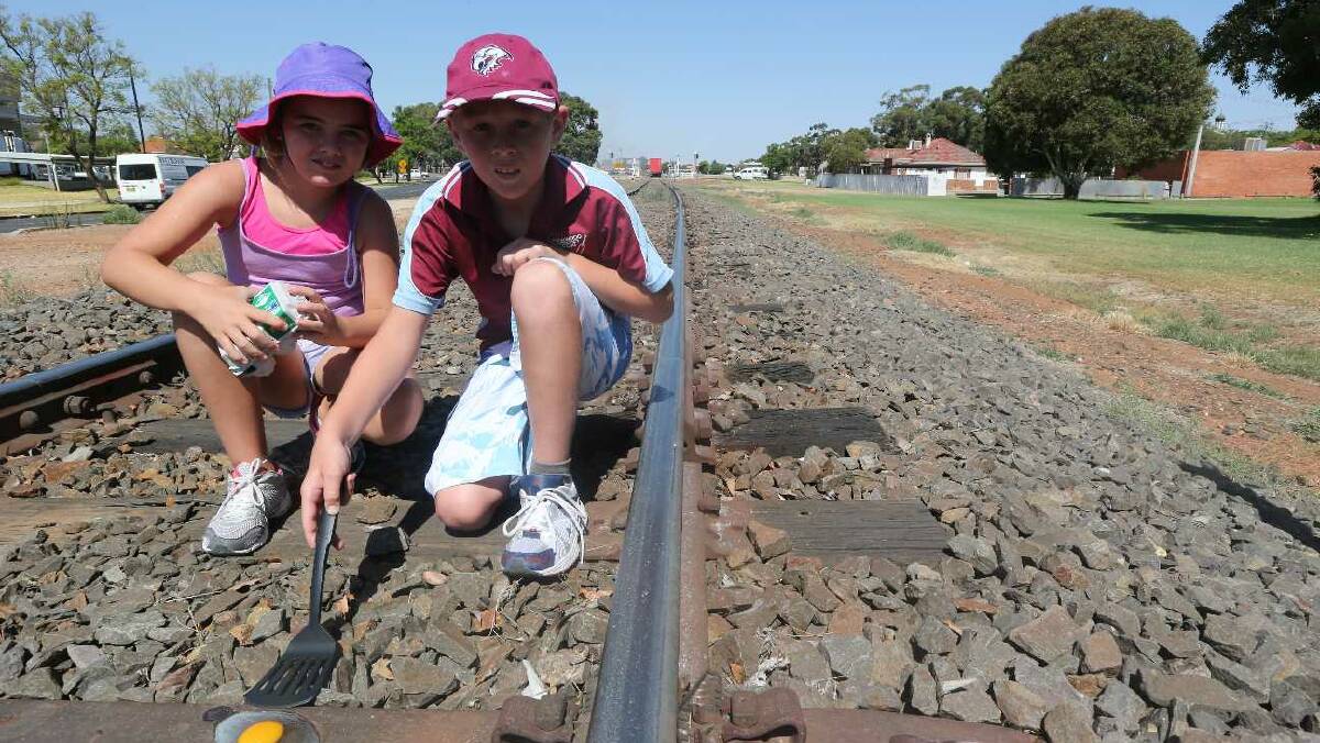 Sam, 11, and Tara, 10, Robinson try to fry an egg on a Griffith railway track. Picture: Anthony Stipo