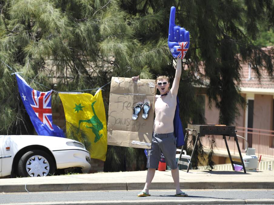 Travis Walsh was doing his patriotic bit for Australia Day by handing out free sausage sangas to passers-by. He cooked up 50 sausages and parked himself out the front of his unit block with the barbie. Picture: Les Smith
